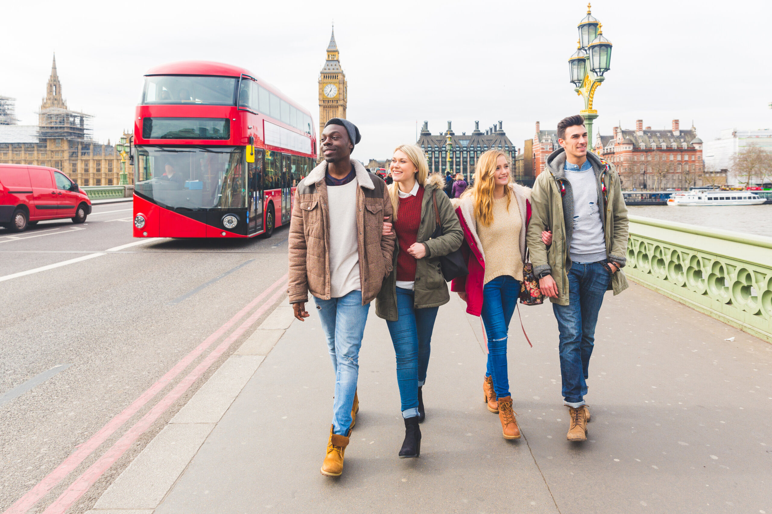 Grupa przyjaciół bawi się w Londynie. Mieszane ludzie rasy śmieją się i cieszą się czasem w mieście. Big Ben i podwójny czerwony autobus na tle.