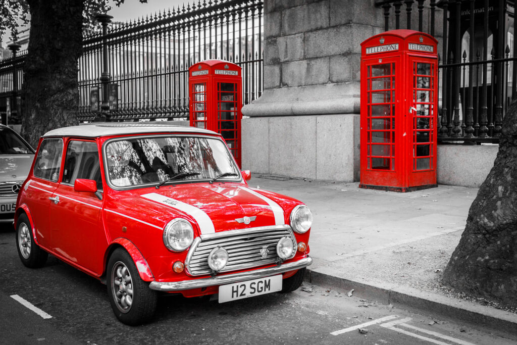 Klasyczny czerwony mini zaparkowany przed dwoma czerwonymi skrzynkami telefonicznych w Londynie