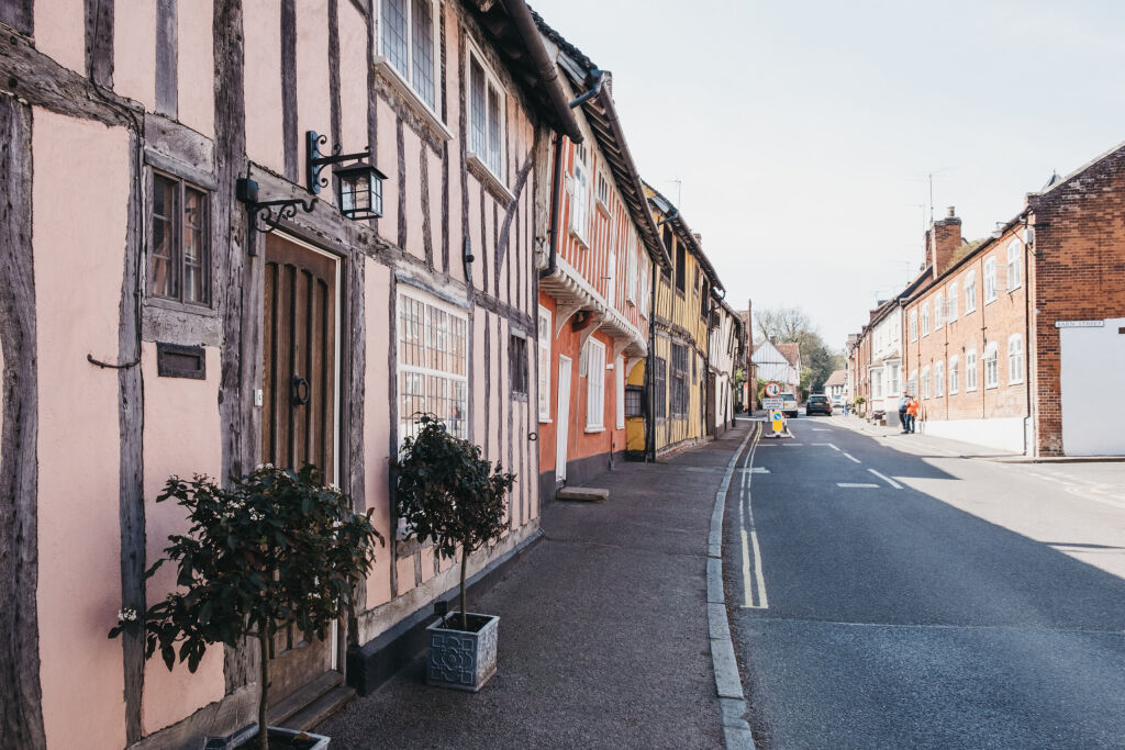 Lavenham, UK - April 19, 2019: Row of half-timbered pastel pink medieval cottages in Lavenham, a village in Suffolk, England, famous for its Guildhall, Little Hall and its architecture.