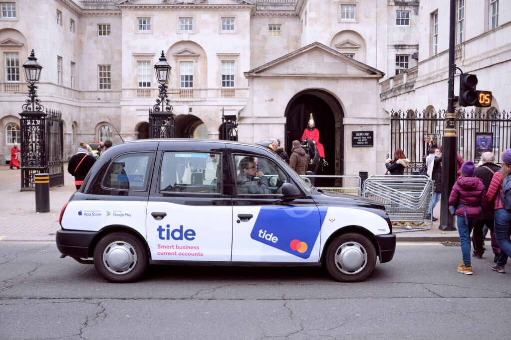 London black cab, with Tide current account advertising, stopped at pedestrian crossing in front of Royal Guard post. London, UK, November 21, 2019