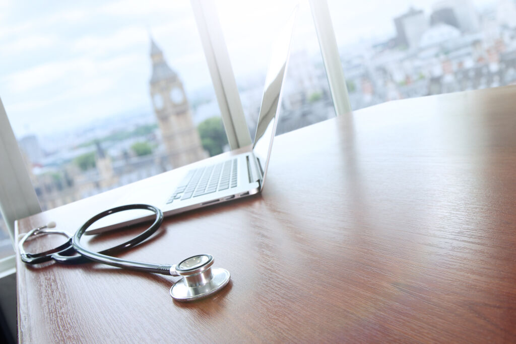 stethoscope and laptop computer on wood table and london big ben blurred background copy space  