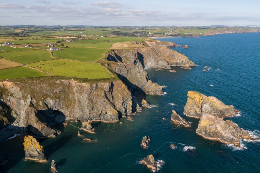Co. Waterford, Ireland - August 2021 : Aerial view of cliffs along copper coast near Tramore town. Visible rock formation locally called in Irish as Trá na mBó located close to Bunmahon beach