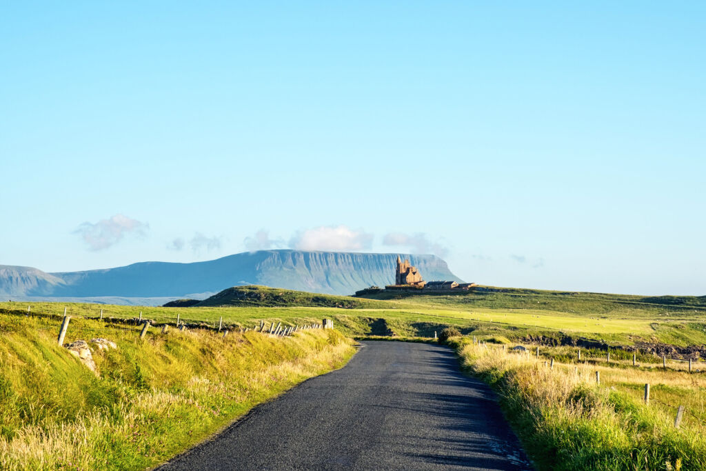 Sligo, Ireland. Famous Classiebawn Castle with Belbulbin mountain at the background in Sligo, Ireland. Sunny day in summer with green grass and blue sky