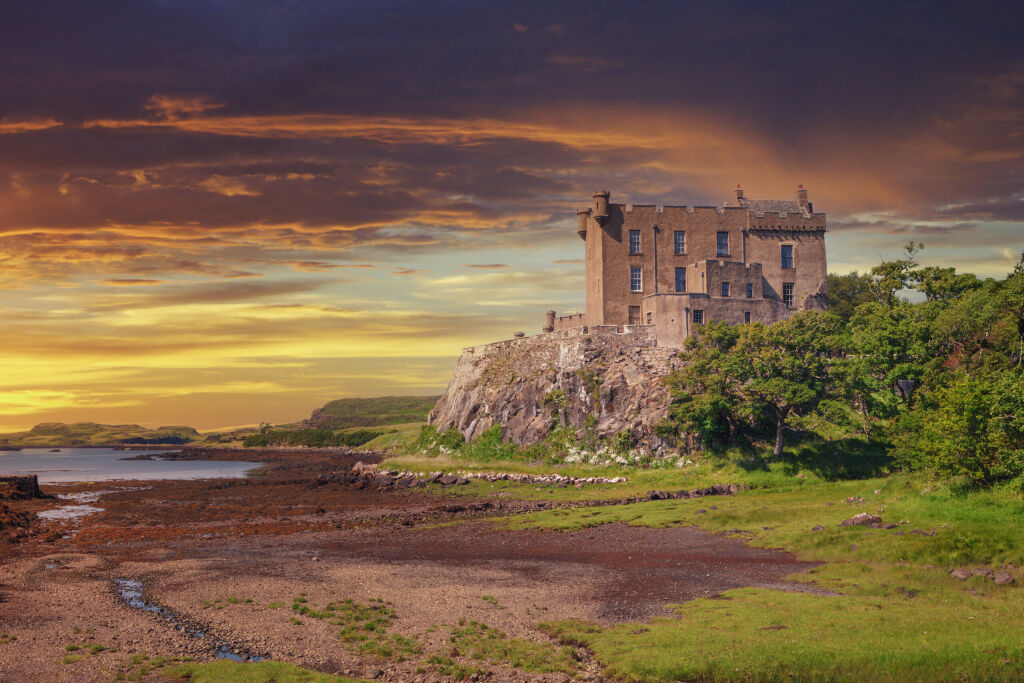 Dunvegan Castle on the Isle of Skye, Scottish Highlands at Loch of Dunvegan, in a dramatic sunset, Scotland, UK