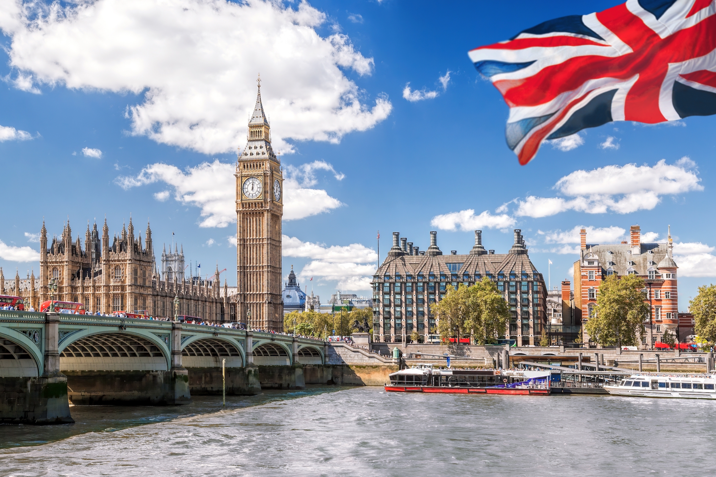 Big Ben z mostem nad Tamizą i flagą Anglii na tle błękitnego nieba w Londynie, Anglia, Wielka Brytania