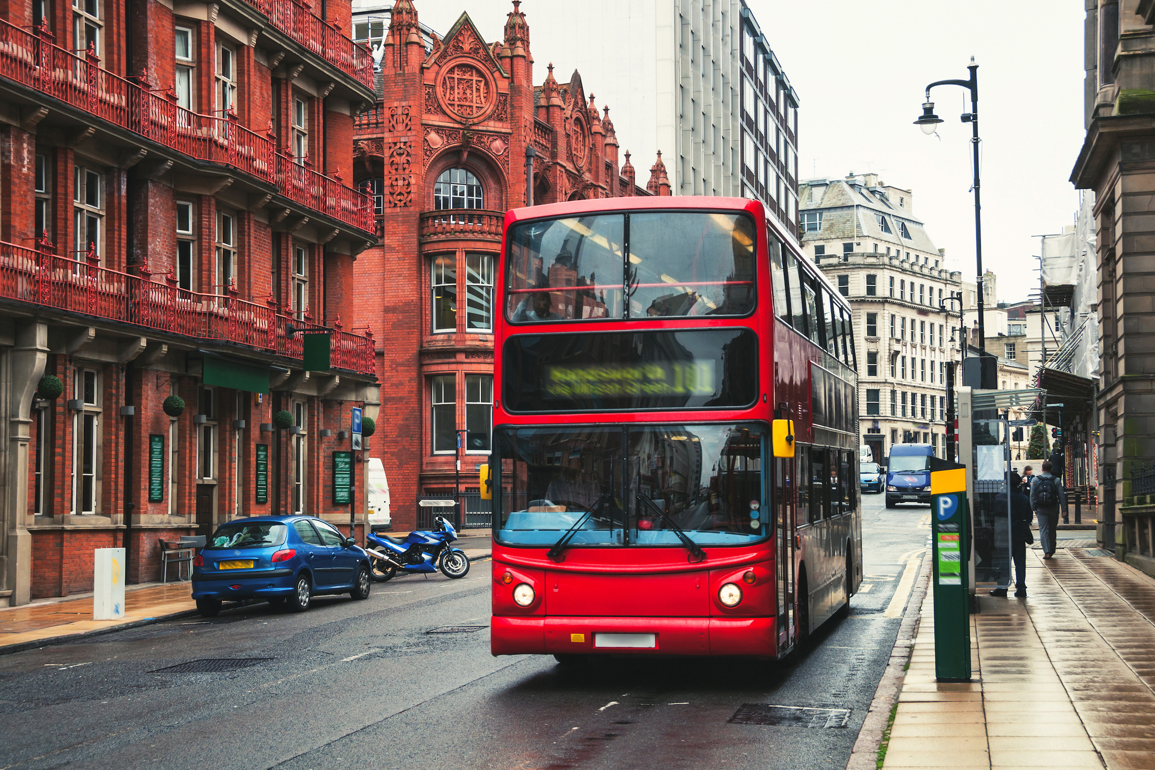 Czerwony piętrowy autobus na ulicy Birmingham, Wielka Brytania. Stary budynek zabytkowej części miasta. Samochody, słynne restauracje i puby