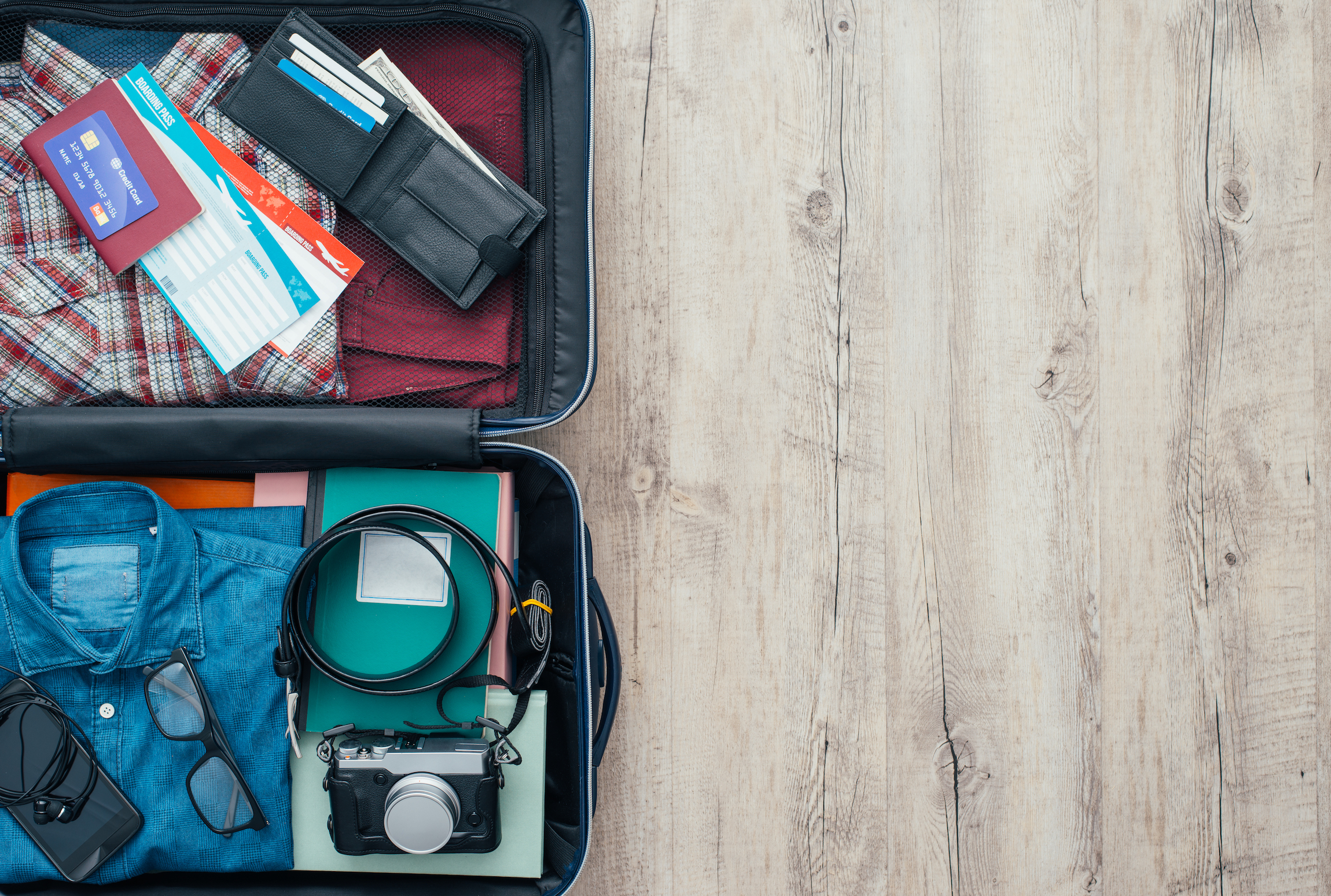 Otwarta torba podróżna z odzieżą, akcesoriami, kartą kredytową, biletami i paszportem, koncepcją podróży i wakacji, płaską