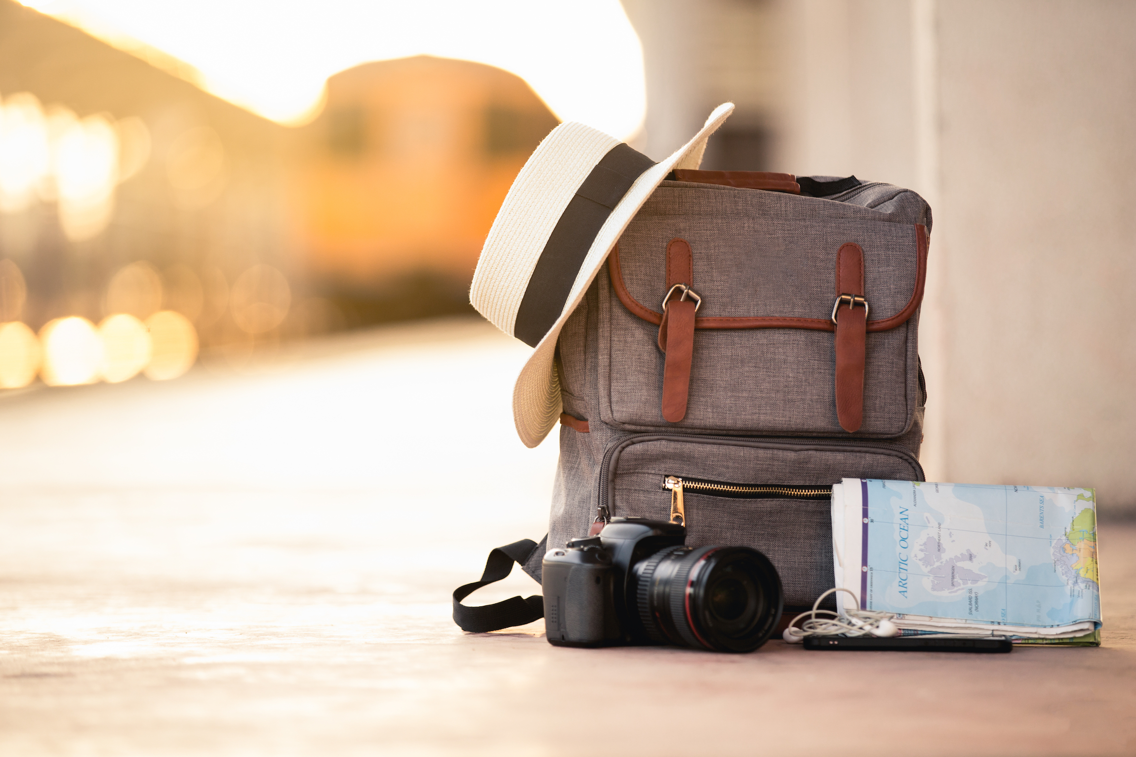 Plecak podróży z kapeluszem, kamerą, mapą, słuchawką i smartfonem na terenie dworca kolejowego o zachodzie słońca pociągu tła. podróż i plecak koncepcja.