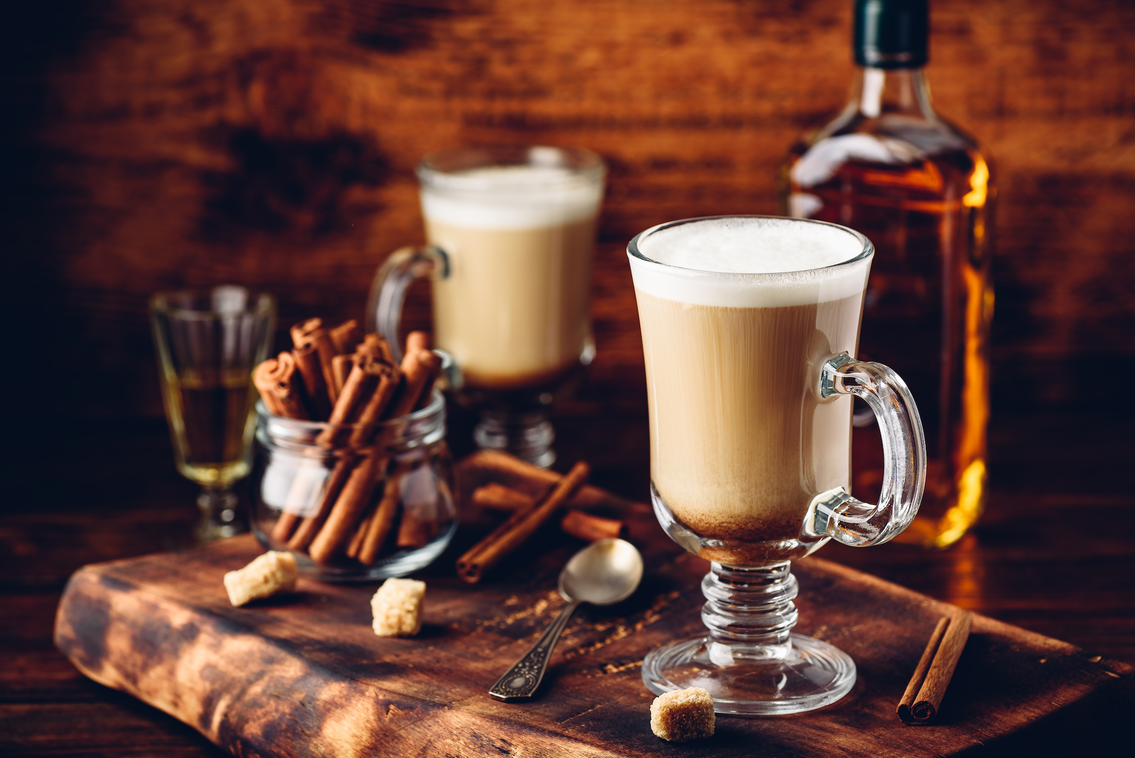 Kawa z irlandzką whisky i bitą śmietaną w szkle na rustykalnej powierzchni drewnianej