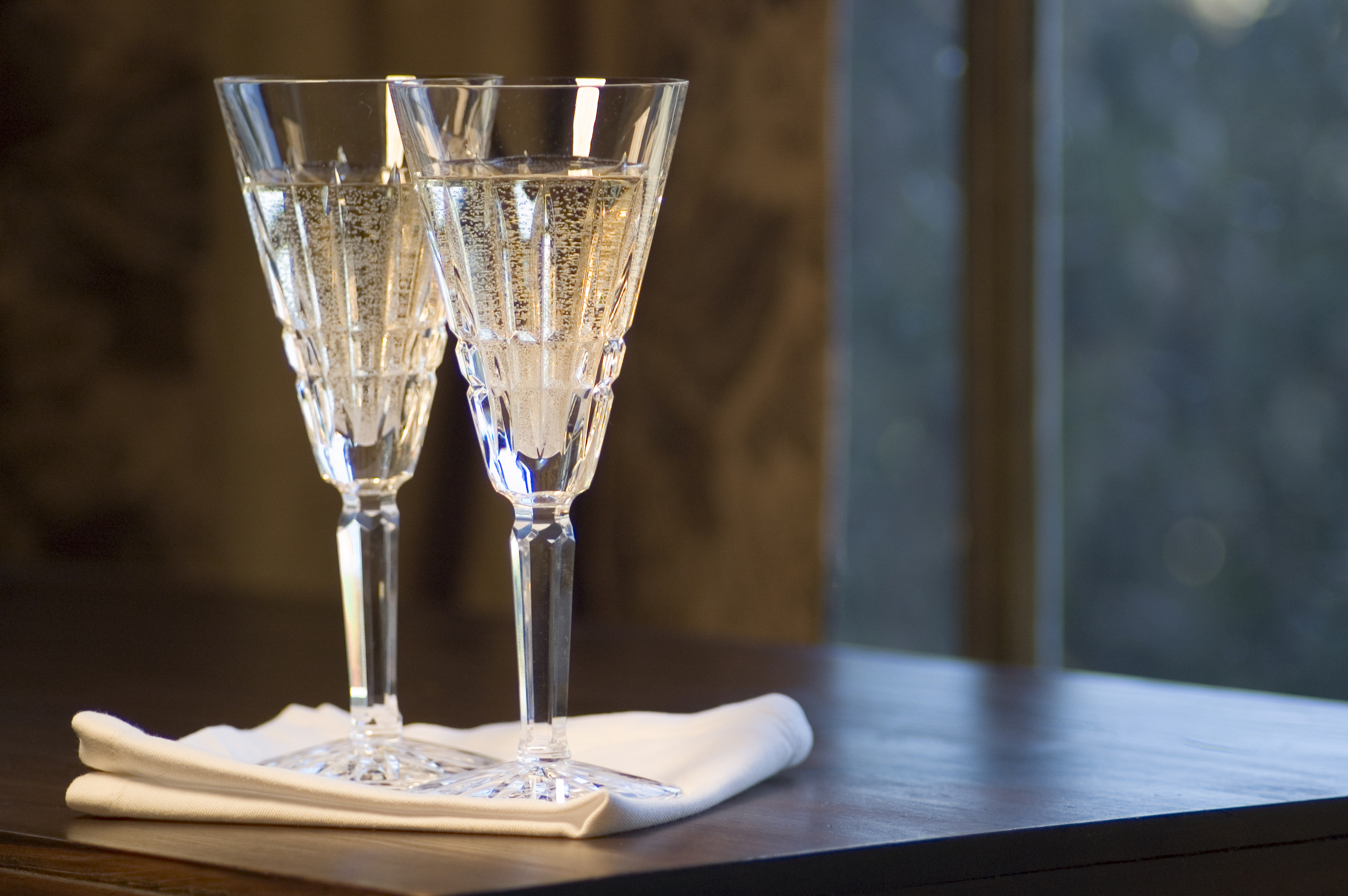 Dwa kieliszki do szampana z kryształu ołowiowego Waterford na ciemnym drewnianym stole. Co kupić w Cork?